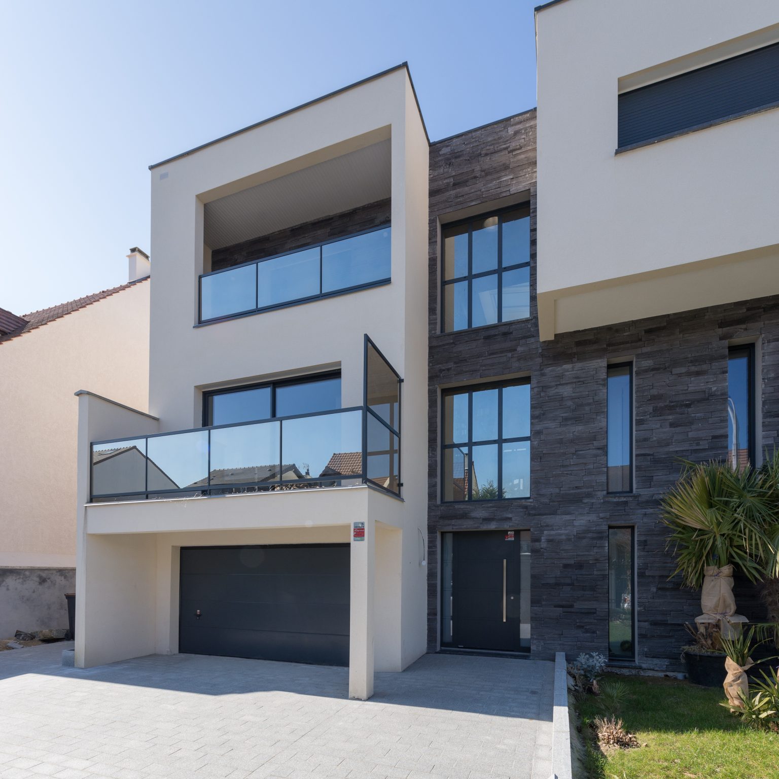 Façade de maison moderne recouvert d'un enduit blanc et de parement Yosemite ton anthracite