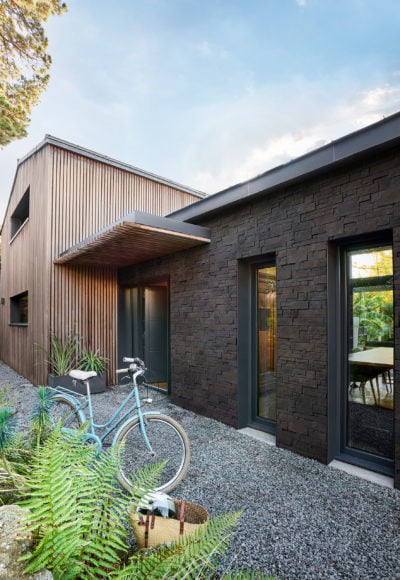 Façade de maison extérieure, d'un côté recouverte d'un revêtement en bois et de l'autre recouvert de parement Cubik ton anthracite de chez ORSOL