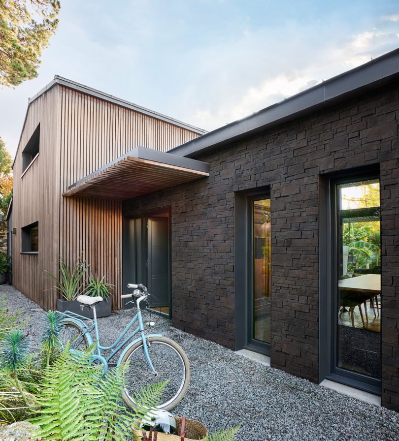 Façade de maison extérieure, d'un côté recouverte d'un revêtement en bois et de l'autre recouvert de parement Cubik ton anthracite de chez ORSOL