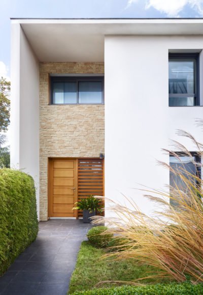 Façade de maison moderne blanche avec entrée abritée recouvert de plaques de parement Tahoe en ton naturel de chez ORSOL