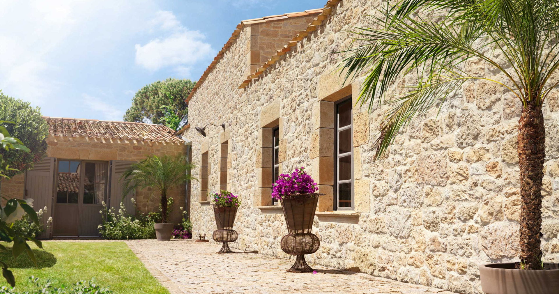 Cour d'une maison en brique avec recouvrement des murs en parement Manoir ton terre de sienne. Quatre fenêtres et une porte entourées d'angles et de linteaux de la gamme Manoir de chez ORSOL