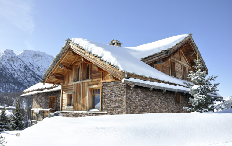 Un chalet de montagne avec parement "Roca" de la marque ORSOL est niché dans un paysage enneigé. Le chalet présente une harmonieuse combinaison de bois naturel et de pierres de parement grises qui lui confèrent un aspect à la fois rustique et élégant.